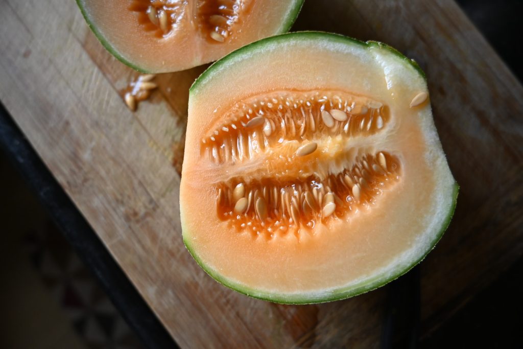 a cut in half Muskmelon on a cutting board